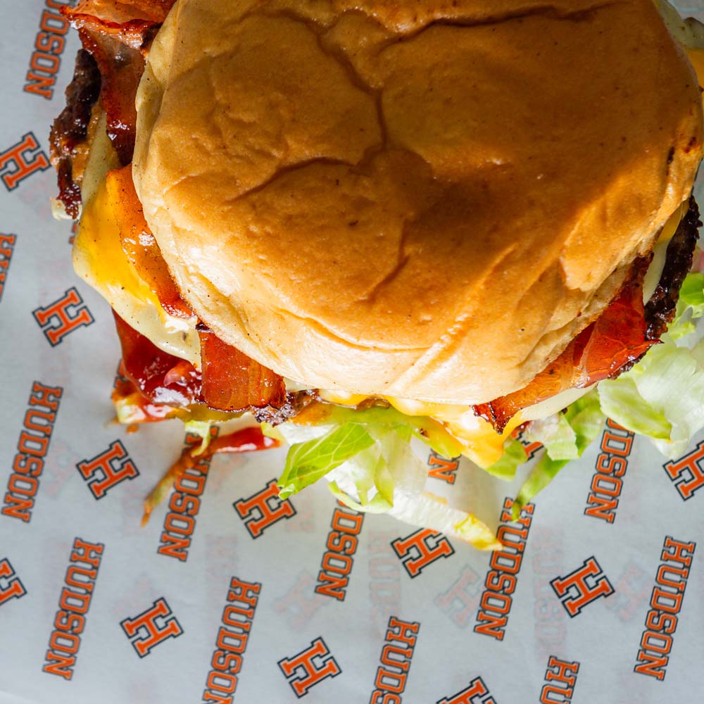 Gourmet burger wrapped in custom-printed greaseproof paper with restaurant logo